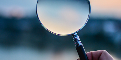 Image of a hand holding a magnifying glass